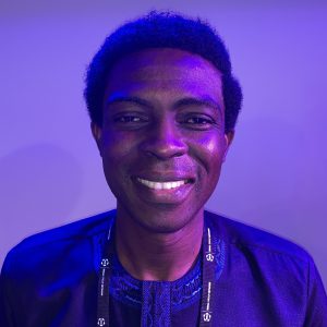 Joseph smiling in a room with blue lighting