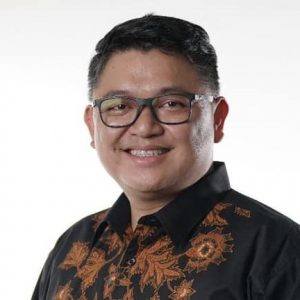 Fernando smiling with a gold patterned button down shirt