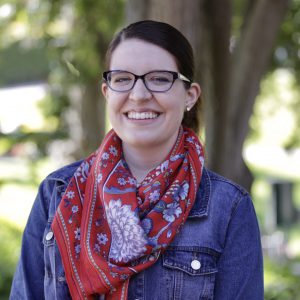 Kiersten smiling outside wearing a red scarf