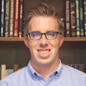 James smiling in front of a bookshelf