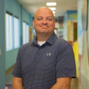 Brian smiling in a blue hallway