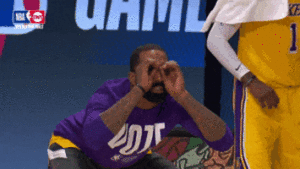 man holding hands over eyes like binoculars at a basketball game 