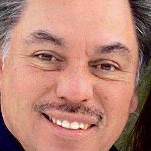 Manuel smiling in a dark dress shirt