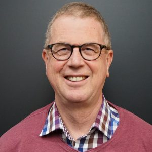 Stephan smiling in a red sweater and collared shirt